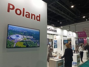 zdjęcie przedstawiajace halę targową w napisek Poland i zdjęciem Stadionu Śląskiego na telebimie 